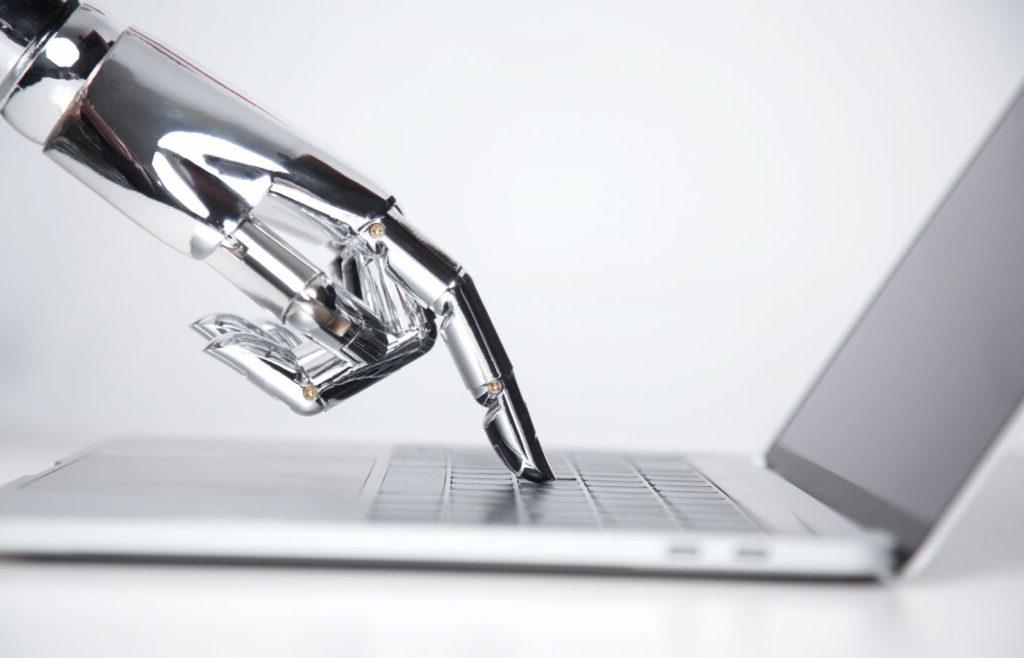 Blog banner showing a robotic hand pressing a laptop keyboard to illustrate the title "Machine Translation vs. human Translation: Will Artificial Intelligence Replace the World’s Second Oldest Profession?"